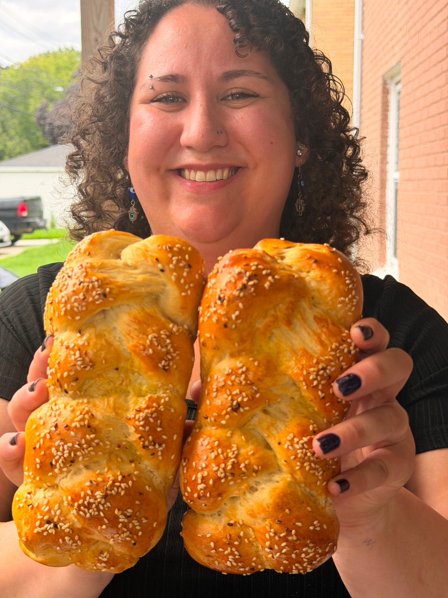Chana Milchtein holding two freshly baked braided challahs